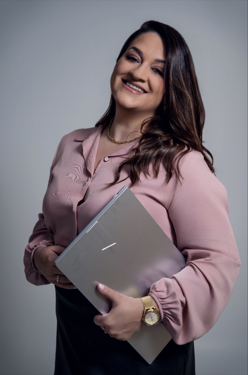 Thaís Cammargo sorrindo, segurando um notebook